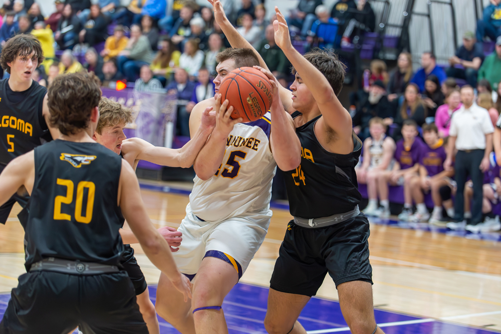 Kewaunee’s Braxton Riha, middle, does his best to maintain possession of the ball against a swarm of Algoma defenders as the Storm and the Wolves squared off in the regular season finale on Friday, Feb. 22
